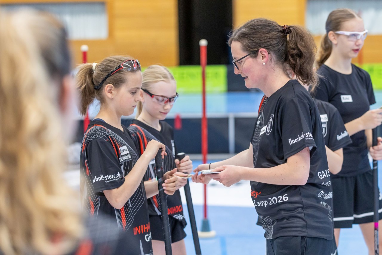Die Trainerin verteilt den Unihockeyspielerinnen Karten.