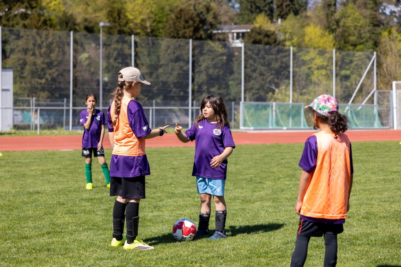 Junge Mädchen spielen Fussball auf dem Fussballfeld.