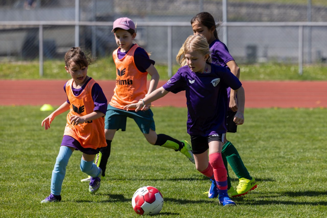 Junge Mädchen spielen Fussball auf dem Fussballfeld.