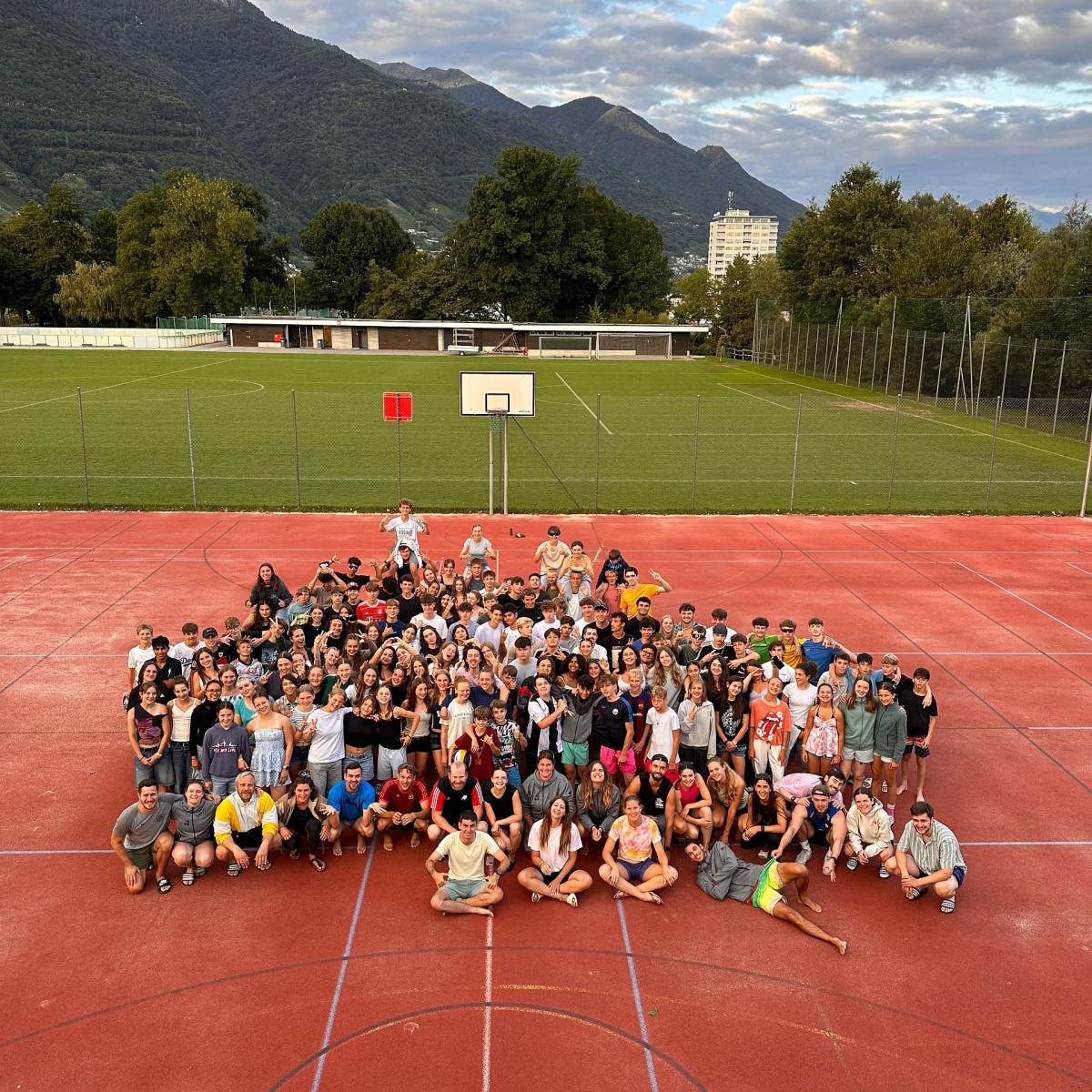 Mehrere Jugendliche stehen auf dem Sportplatz zusammen für ein Gruppenfoto.