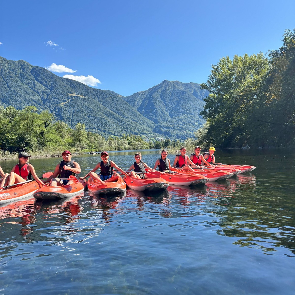 Jugendliche sitzen in ihrem Kanu und posieren für ein Gruppenfoto.