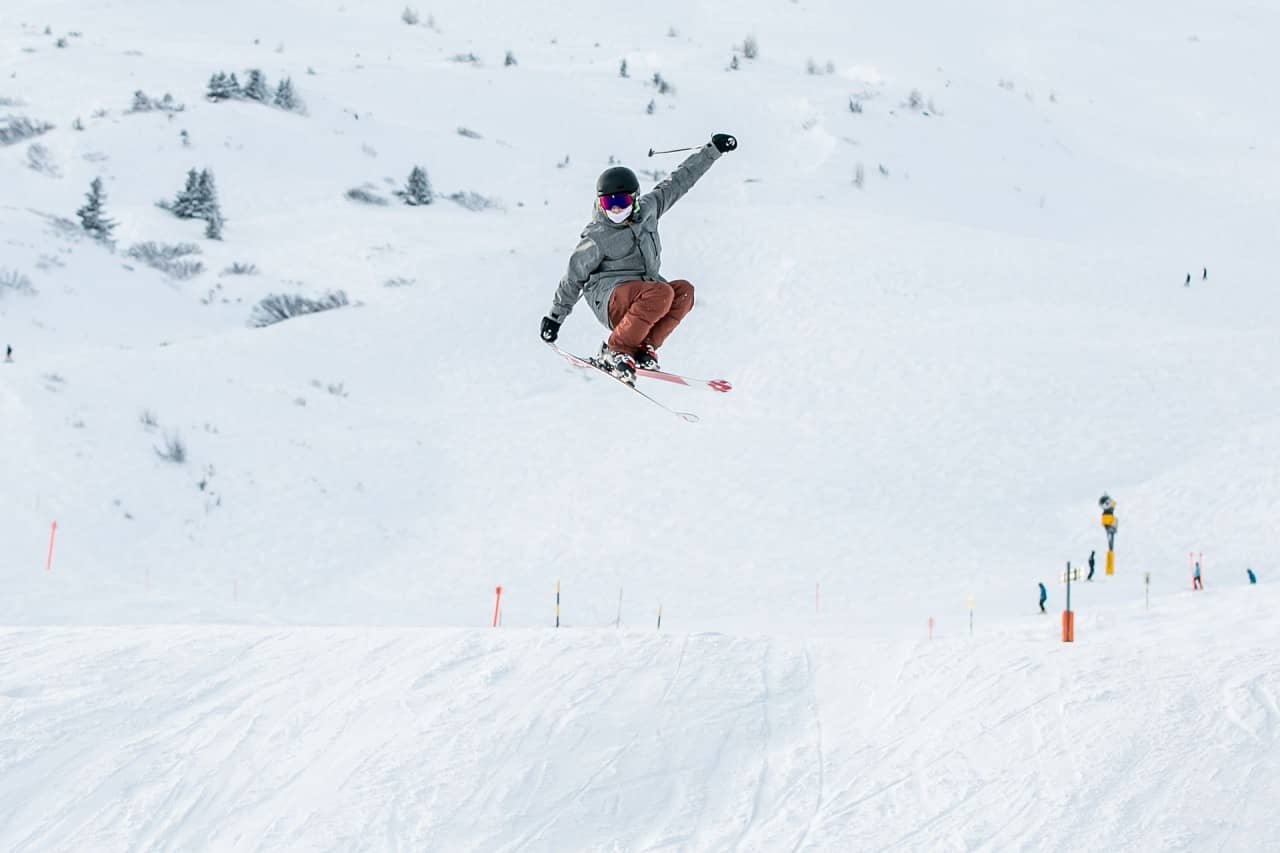 Ein Skifahrer auf der Piste springt über eine Schanze.