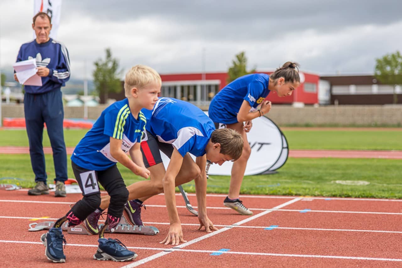 Jugendliche mit einer Beeinträchtigung stehen an der Startlinie im Leichtathletik.