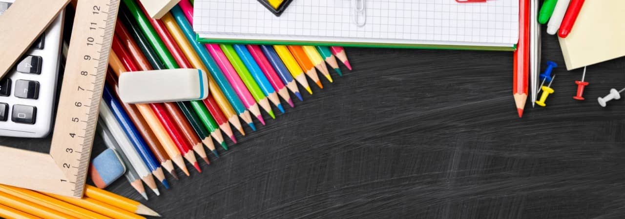 Schwarze Schieferwandtafel mit Schreib-, Mal- und sonstigen Schuluntensilien darauf
