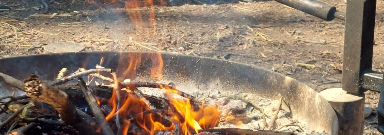 Ausschnitt einer offenen Feuerstelle im Freien, Flammen steigen hoch.