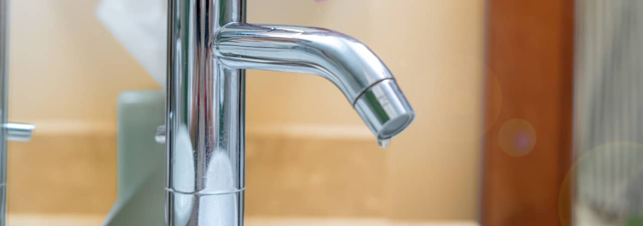 Hand greift an silbrigen Wasserhahn