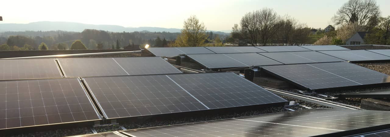 Solarpanel auf einem Hausdach im Mittelland. Im Hintergrund sind bewaldete Hügel zu sehen.