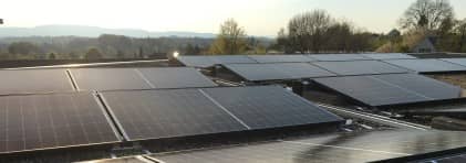 Solarpanel auf einem Hausdach im Mittelland. Im Hintergrund sind bewaldete Hügel zu sehen.