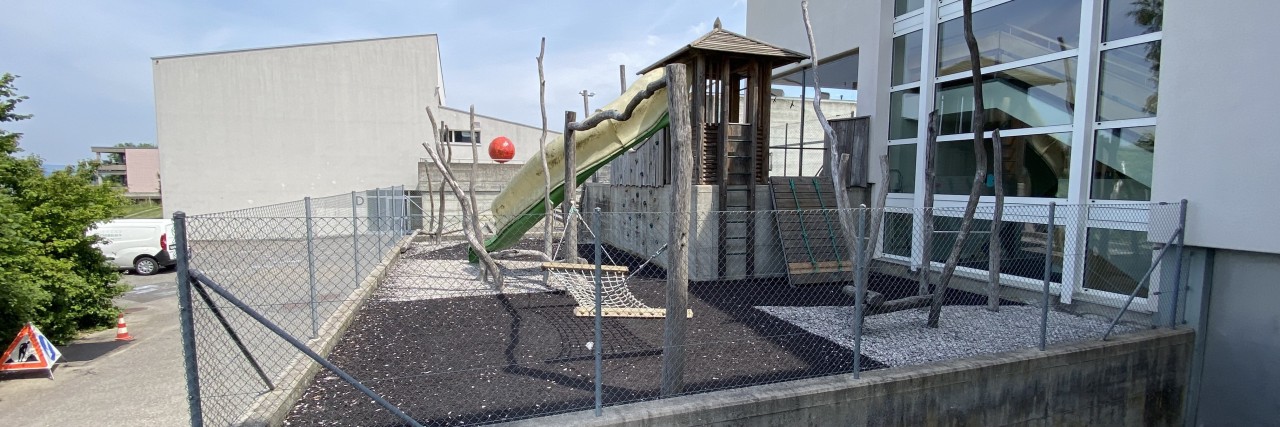 Das Bild zeigt einen naturfernen Spielplatz mit dunklen Plastikoberflächen, welche sich im Sommer schnell erhitzen.
