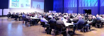 Blick in eine Saal, in dem die Teilnehmenden an Tischen gemeinsam diskutieren.