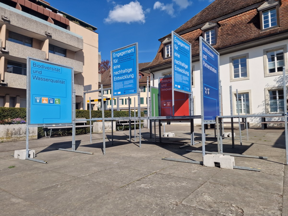 Infostelen einer Outdoor-Ausstellung auf einem Platz, mit Text Biodiversität und Wasserqualität sowie Engagement für eine nachhaltige Entwicklung.