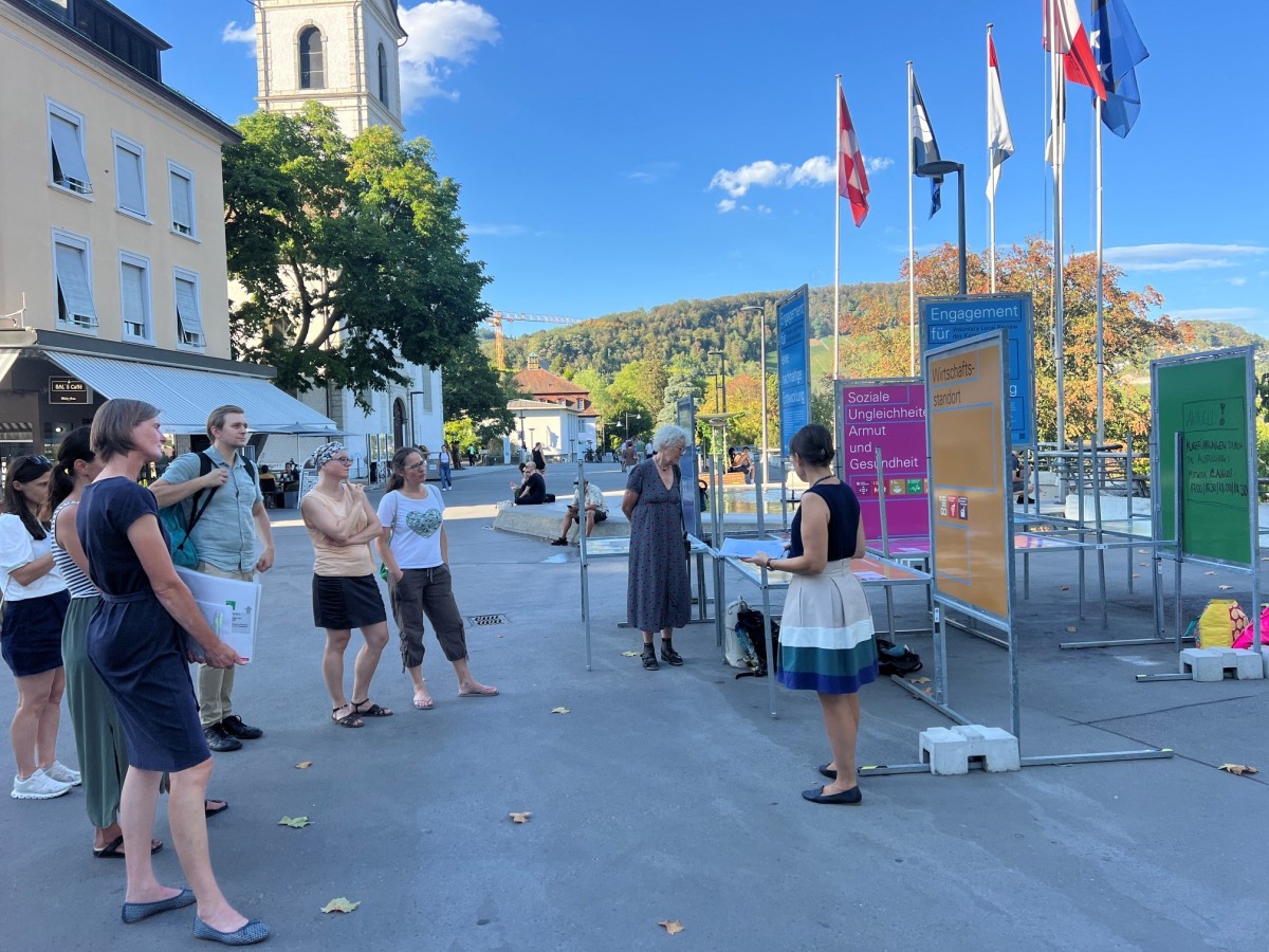 Das Bild zeigt die Ausstellung in VLR mit einer Besuchergruppe auf dem Unteren Bahnhofplatz Baden.
