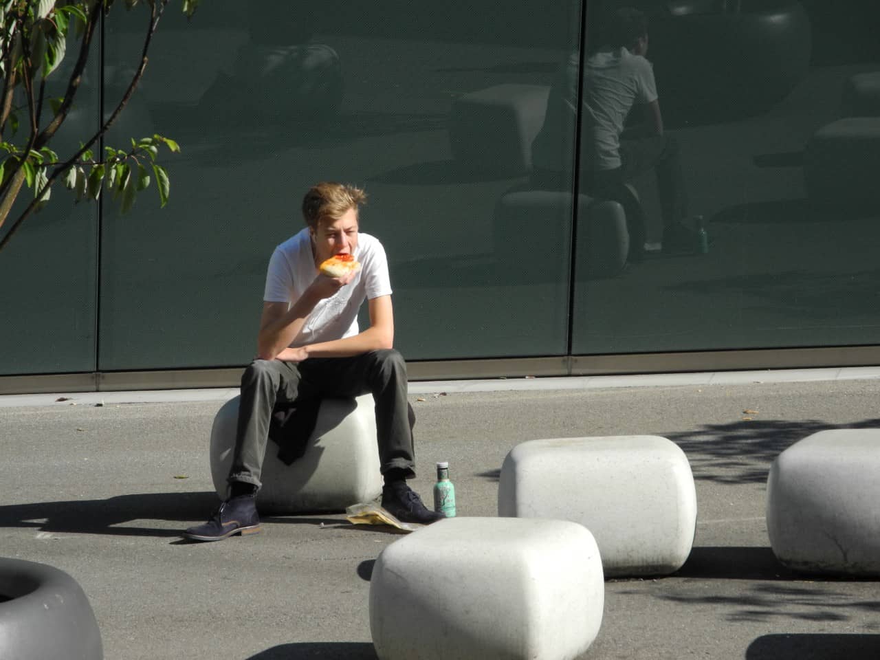 Eine junge Person sitzt auf einem Betonelement.