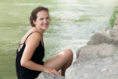 Portrait von Karin, die am Flussufer sitzt.