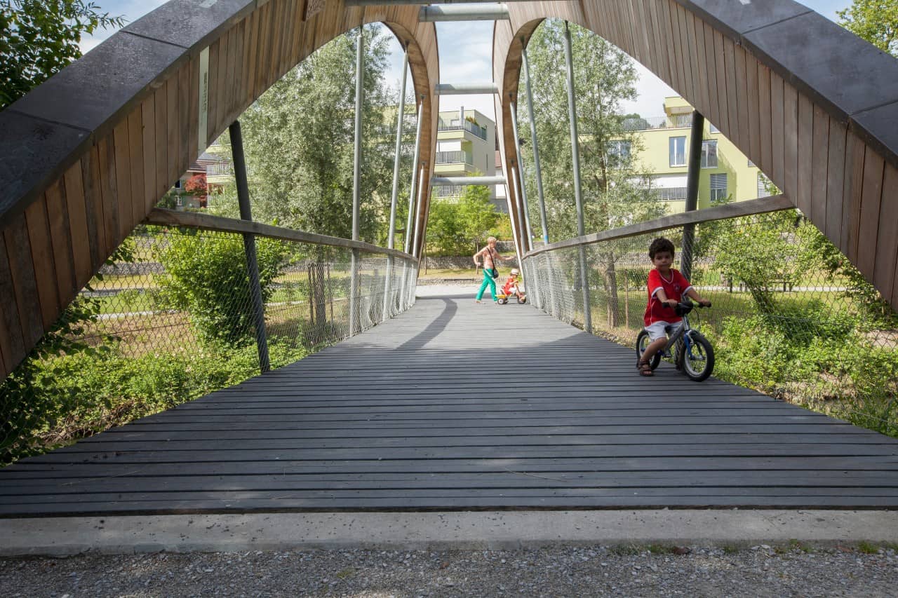 Kinder fahren mit Velos über eine Holzbrücke.