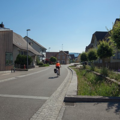 Eine Velofahrerin fährt auf der neu gestalteten Dorfstrasse in Spreitenbach.