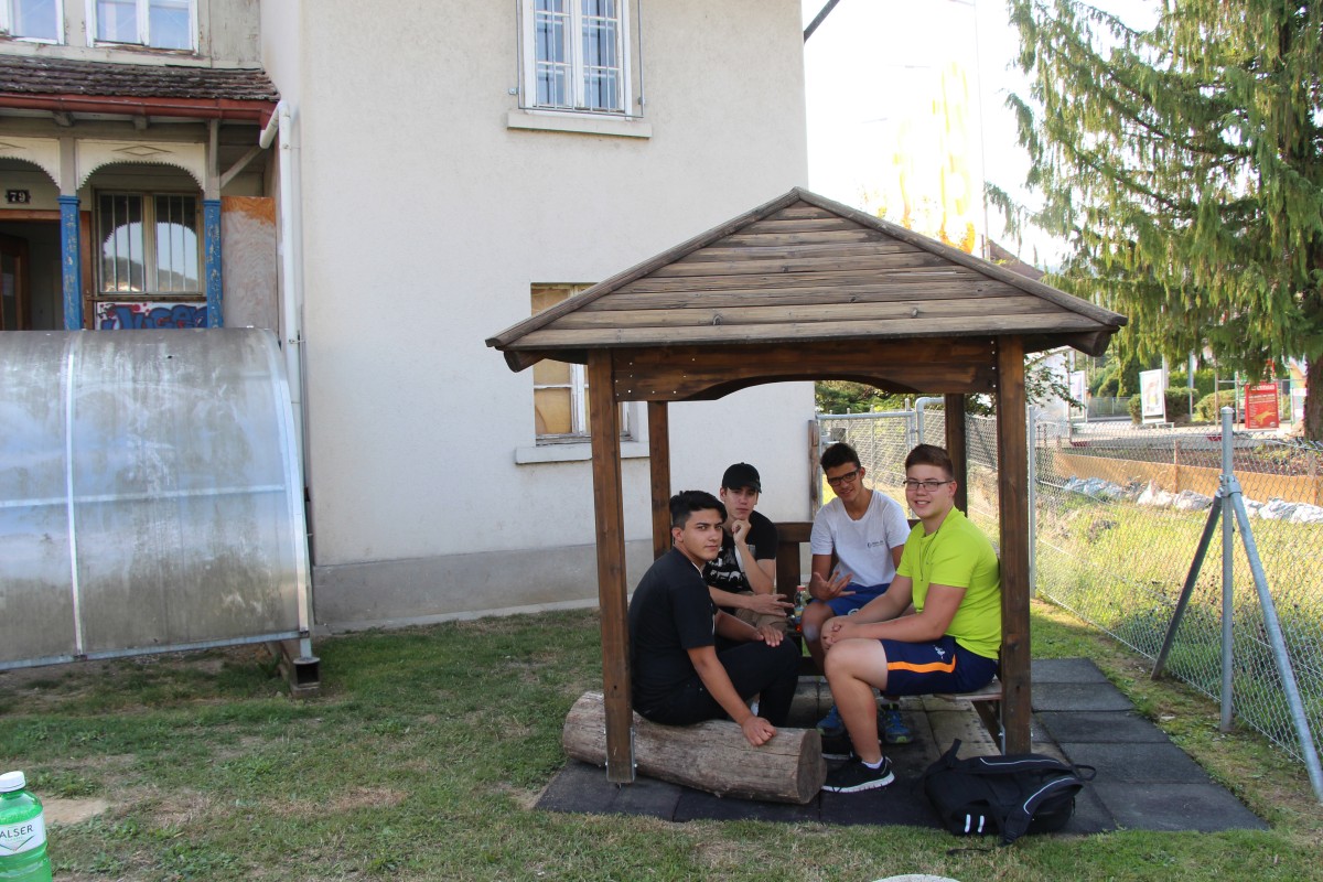 Eine Gruppe von Schülern chillt unterm Dach des kleinen Pavillons neben dem Jugendhaus