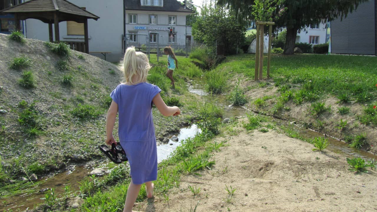 Zwei Mädchen spielen am Bachlauf