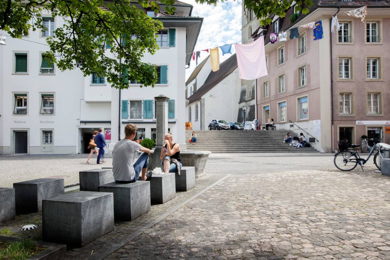 Jugendliche verweilen auf modernen Sitzelementen in der Altstadt von Zofingen.
