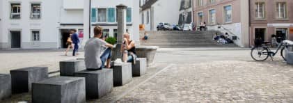 Jugendliche verweilen auf modernen Sitzelementen in der Altstadt von Zofingen.