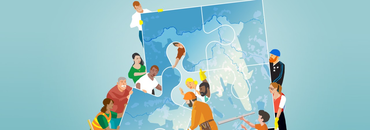 Eine Gruppe von Menschen unterschiedlicher Berufe und Herkunft fügt grosse Puzzleteile zusammen, die eine Landkarte zeigen.