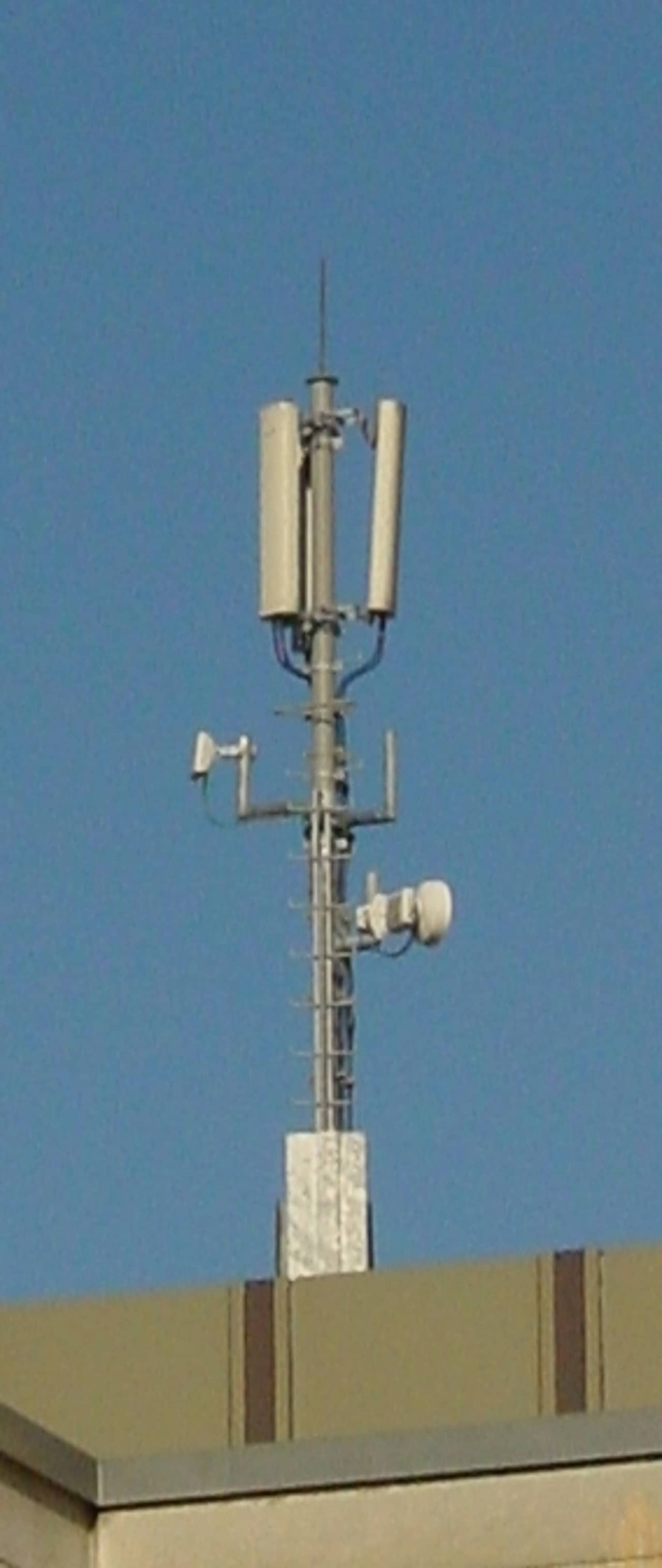 Flachdach mit einem Stahlmasten mit verschiedenen Mobilfunkantennen