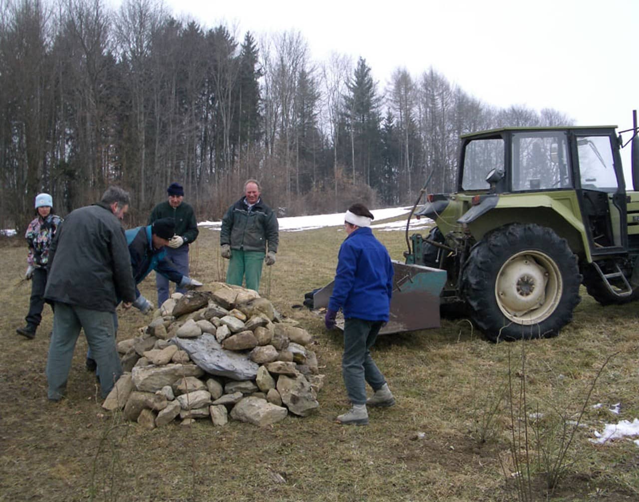 Mehrere freiwillige Helfer schichten einen Steinhaufen auf