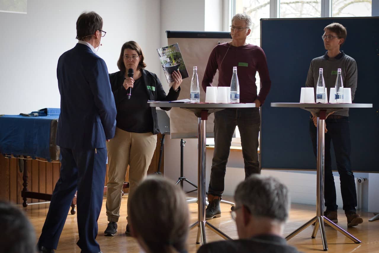 Vier Personen diskutieren gemeisam auf einer Bühne im Rahmen eines Podiums.