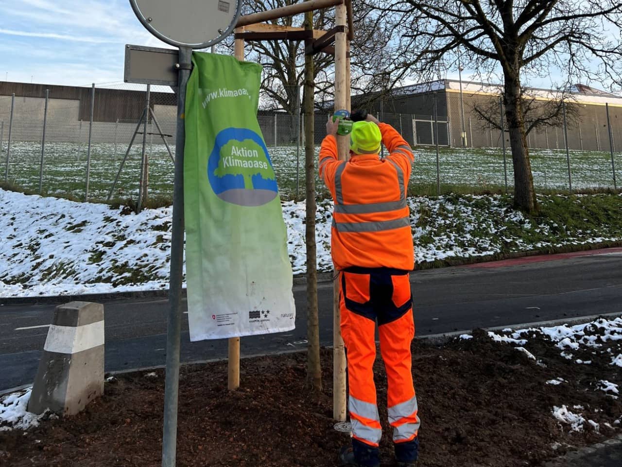 Ein Werkhofmitarbeiter montiert ein Schild