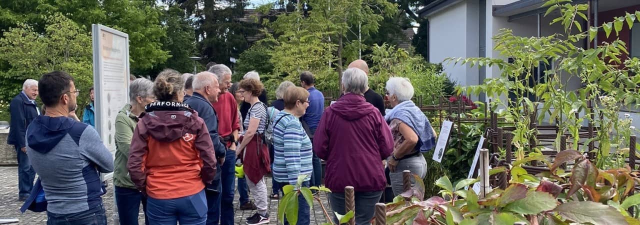 Eine Gruppe von Neobiota-Ansprechpersonen stehen im Kreis und werden über Neophyten informiert