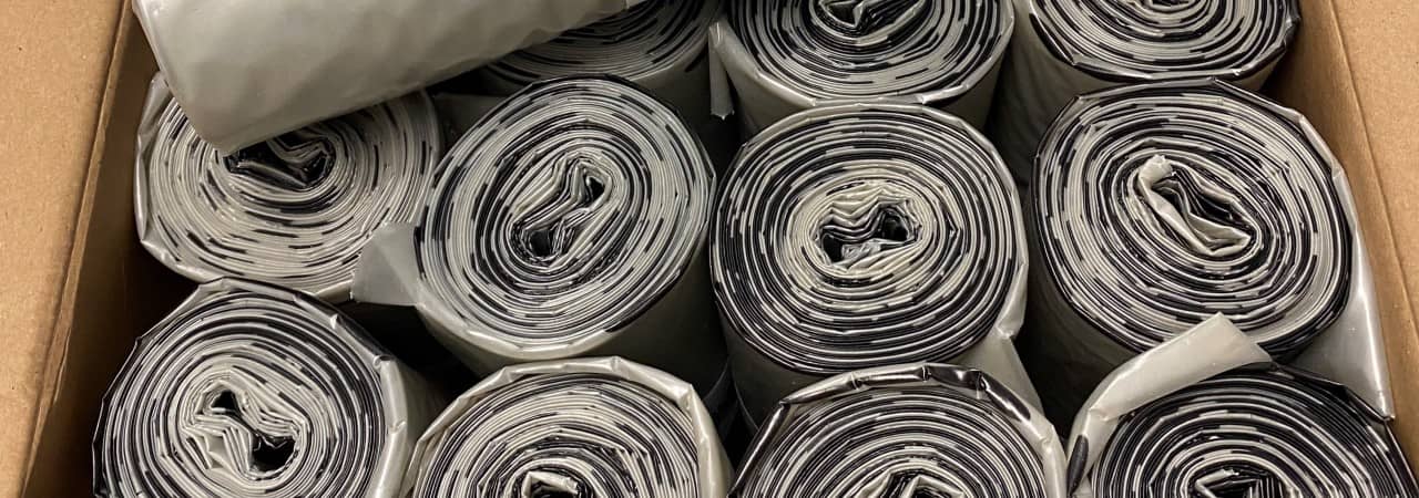Kiste mit Rollen von Plastiksäcken gefüllt.