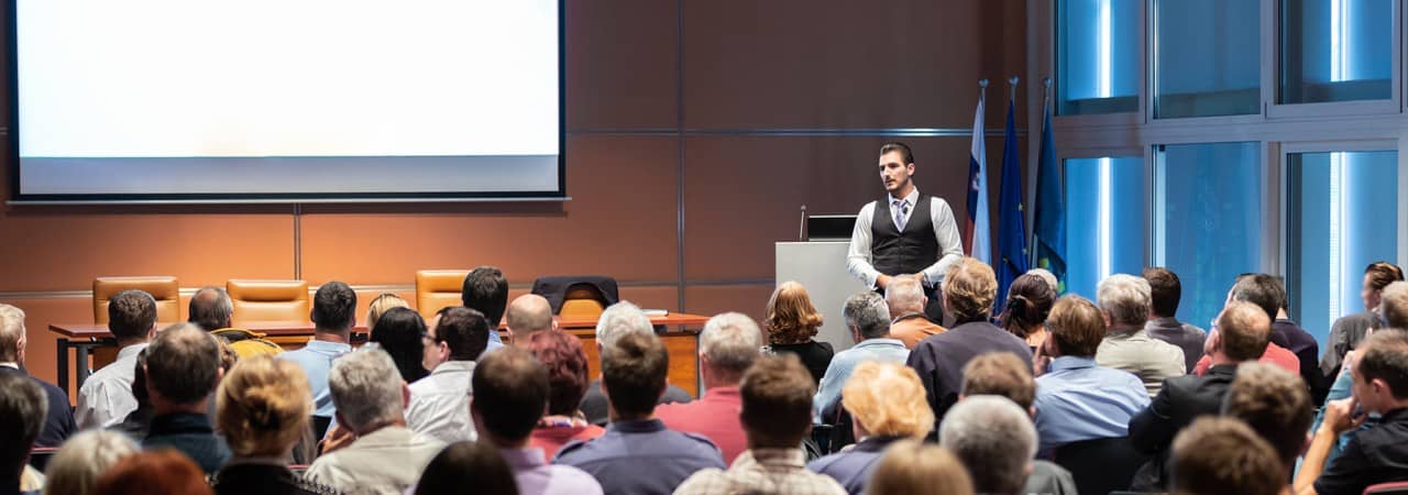 Ein Herr hält ein Referat vor einer Menschenmenge