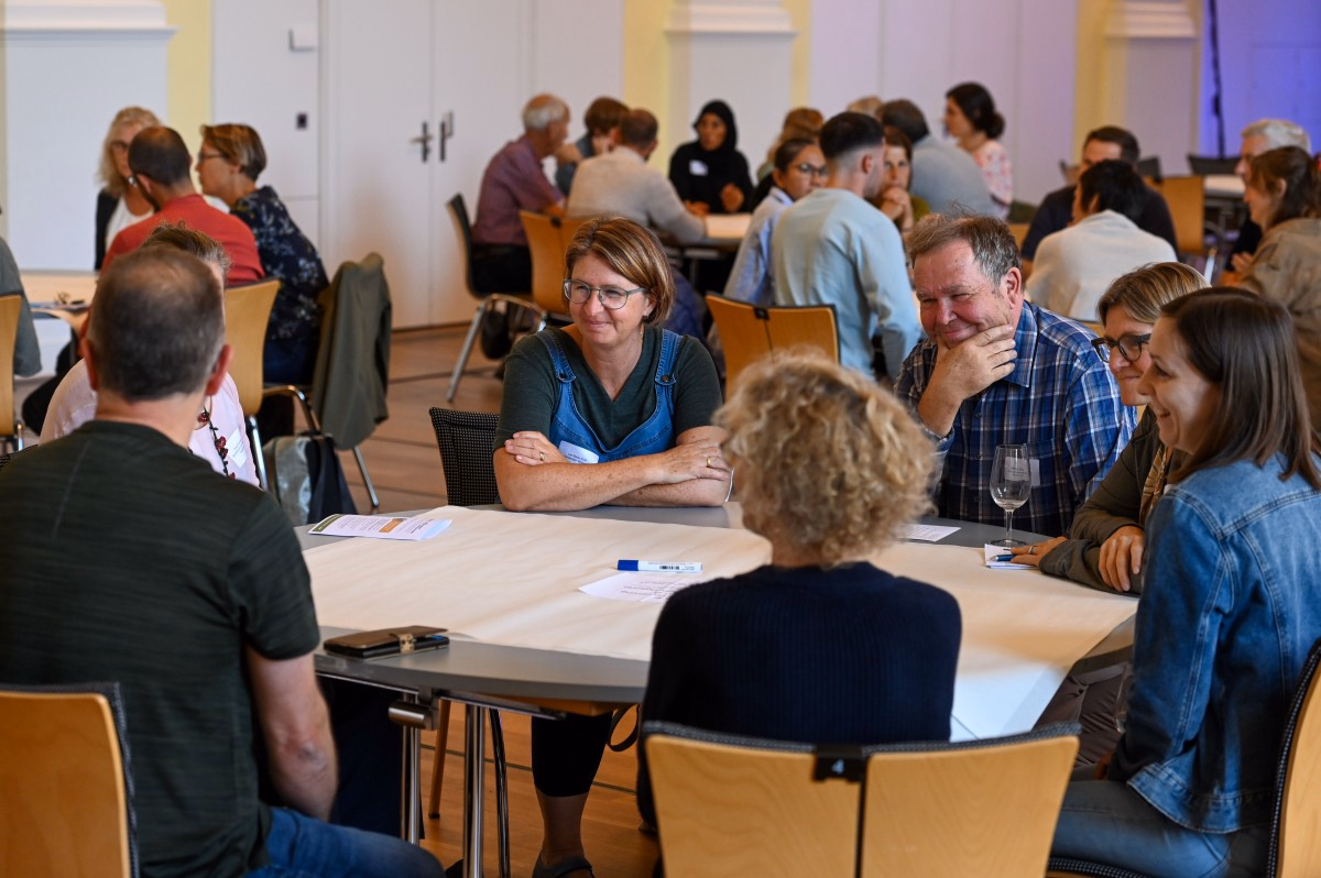 Sieben Personen sitzen an einem Tisch.