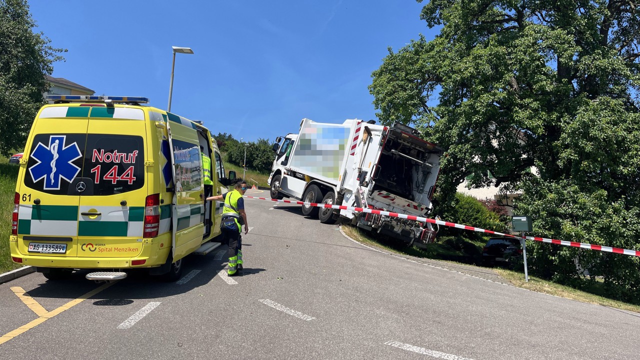 Ein Mülllastwagen der von der Strasse abkam, davor Steht ein Krankenwagen.