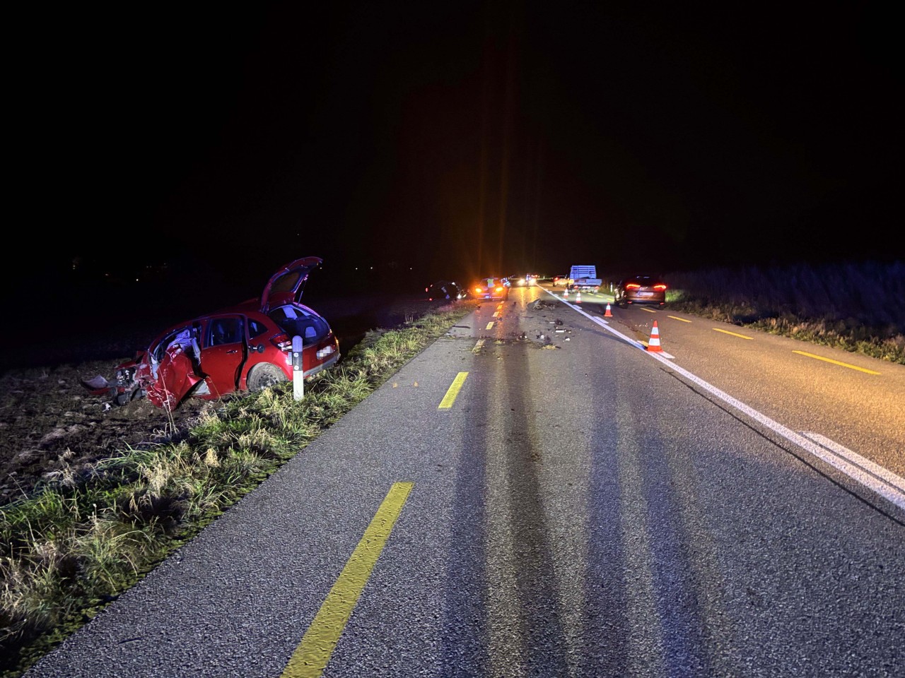 Strasse mit zwei verunfallten Fahrzeugen.Ein rotes sowie ein schwarzes Fahrzeug.