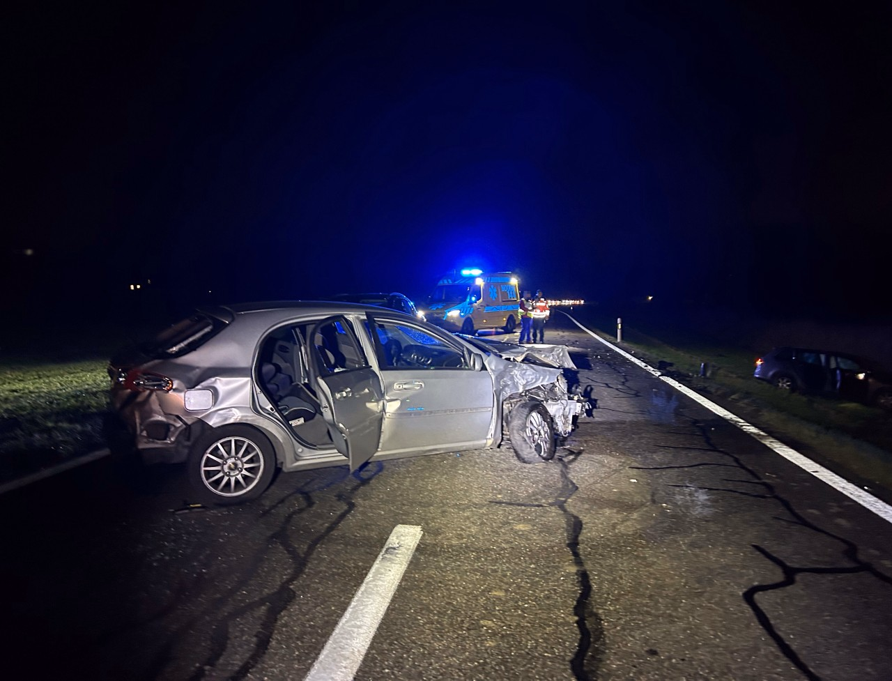 Stark beschädigtes Fahrzeug auf der Strasse. Krankenwagen im Hintergrund. Weiteres Fahrzeug im Wiesland.