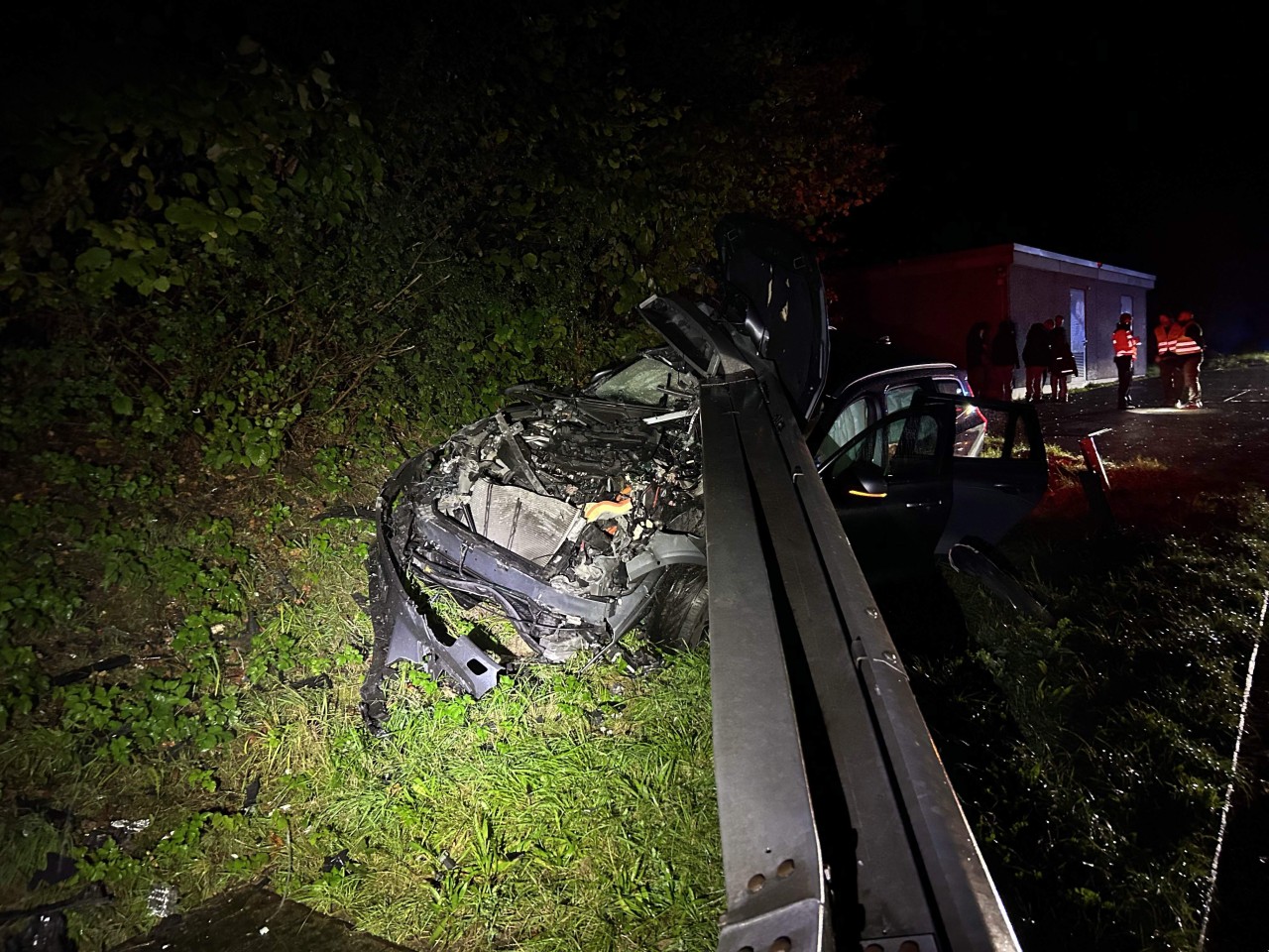 Demolierter Unfallwagen verkeilt unter der Leitplanke.