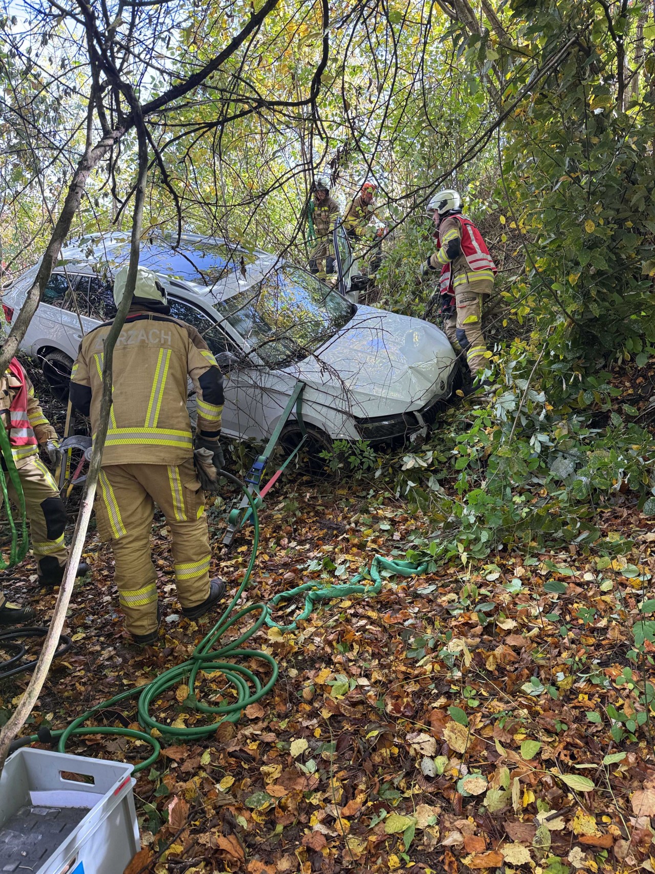 Demolierter Unfallwagen im steilen Gelände hängend.