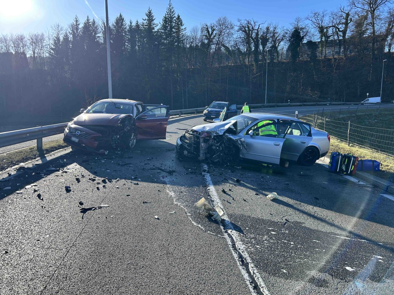 Ein silberner Audi ond ein roter Volvo, welche vorne stark beschädigt sind, mittig auf Strasse.