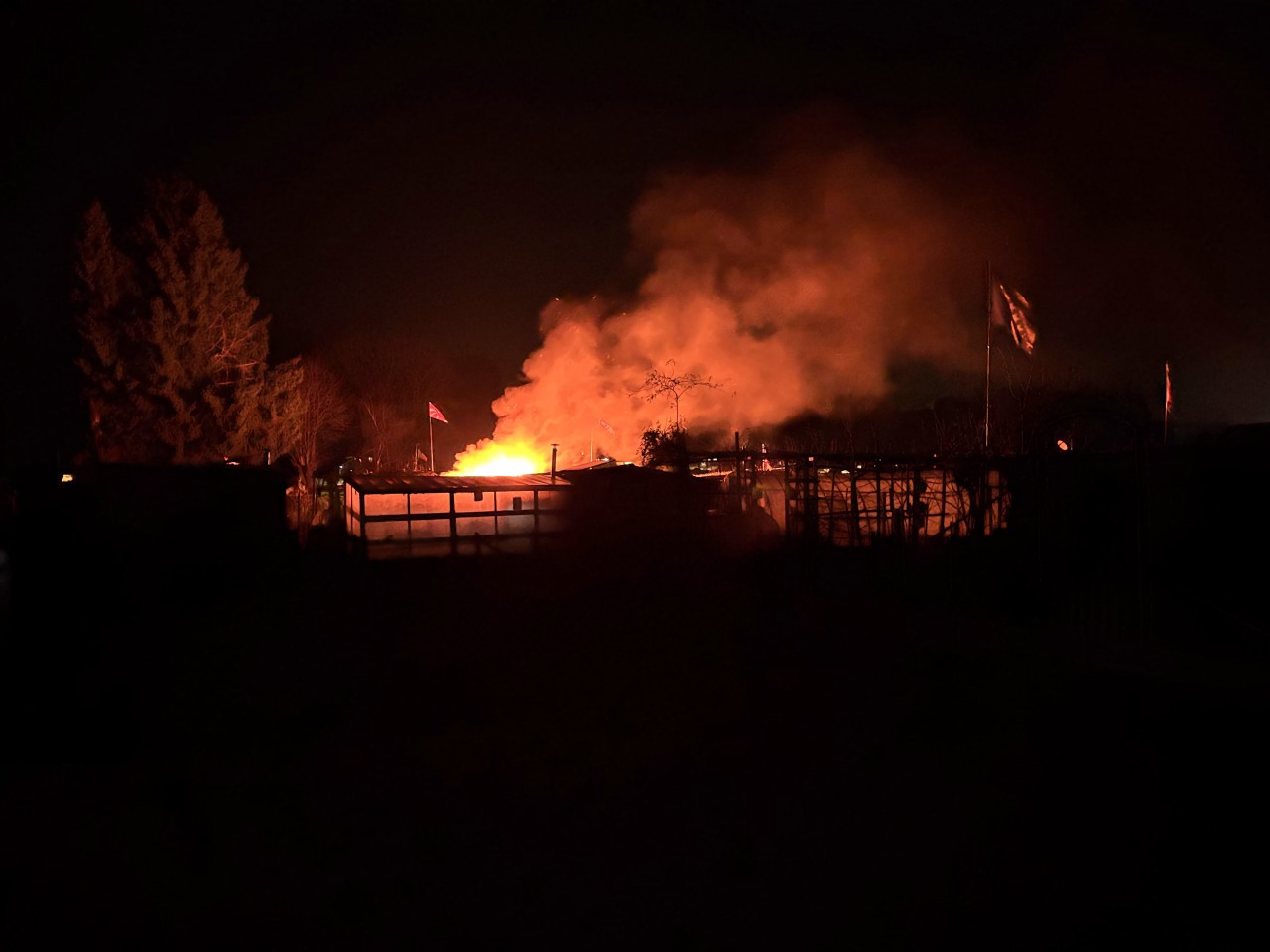 Flammen inkl. Rauch im Nachthimmer über Schrebergärten ersichtlich.