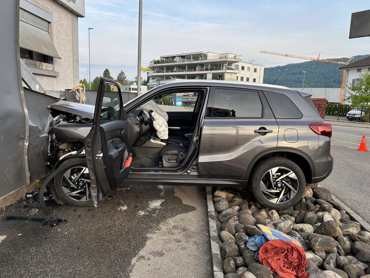 Grauer SUV, welcher frontal mit einer Sichtschutzwand kollidiert ist. Front ist komplett eingedrückt und Airbags sind ausgelöst.