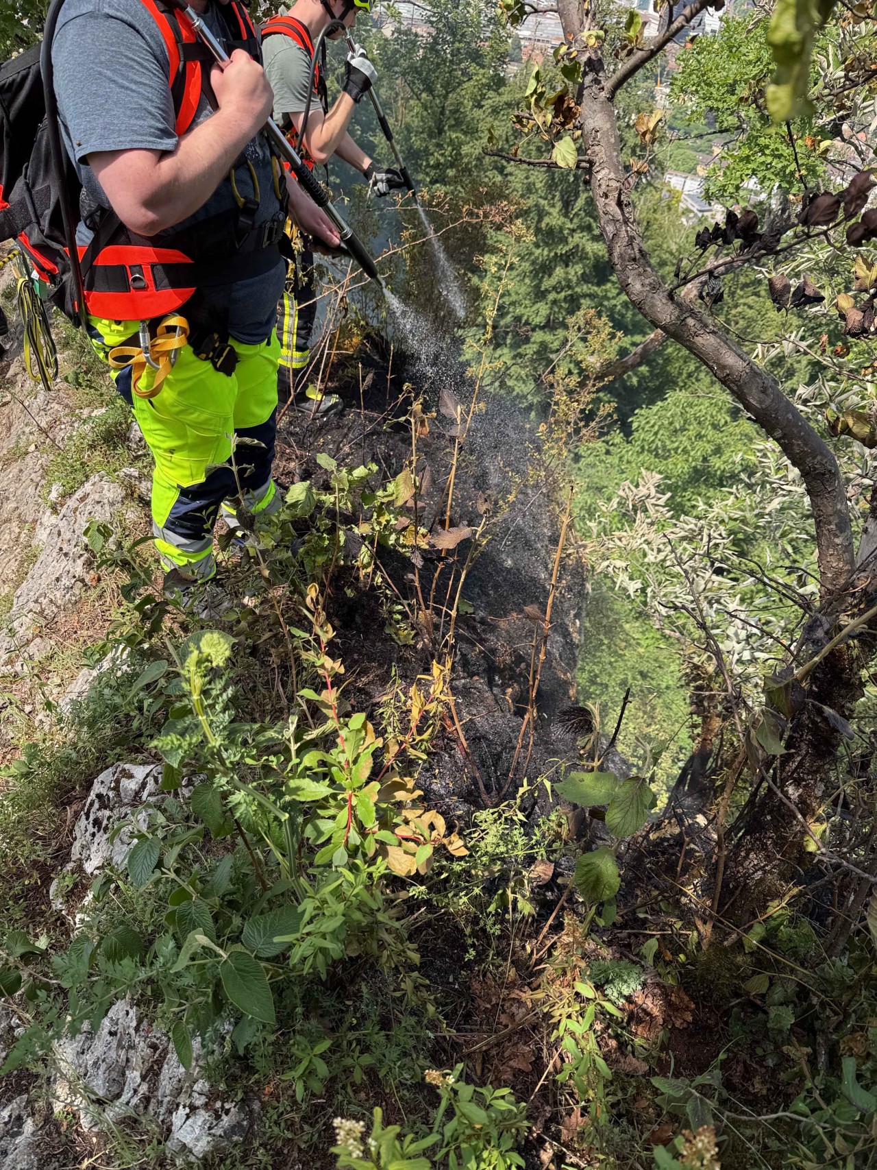 Zwei Feuerwehrleute, welche mit Handspritzen ein Schwellbrand löschen.