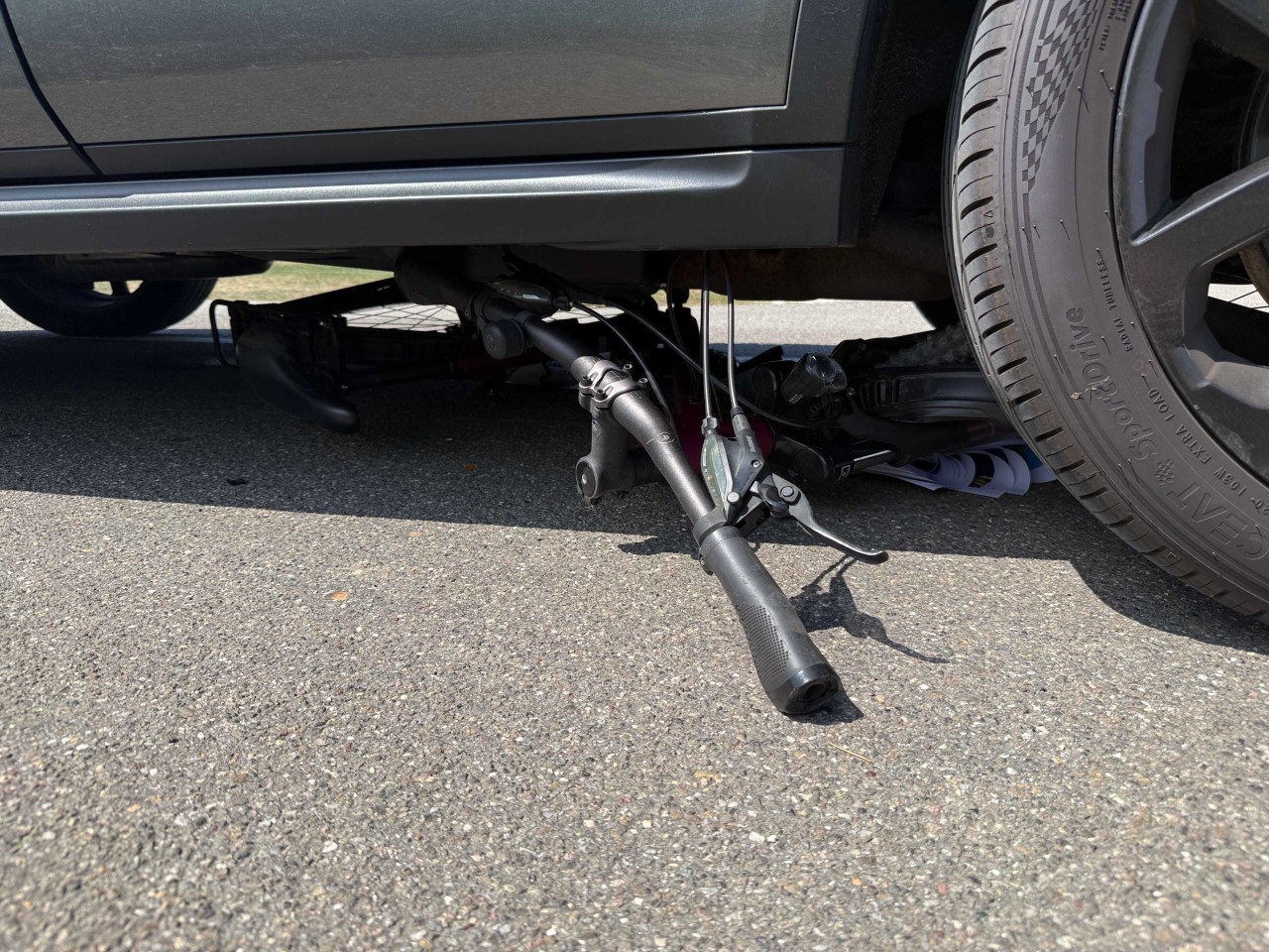 Fahrrad unter einem Personenwagen eingeklemmt.