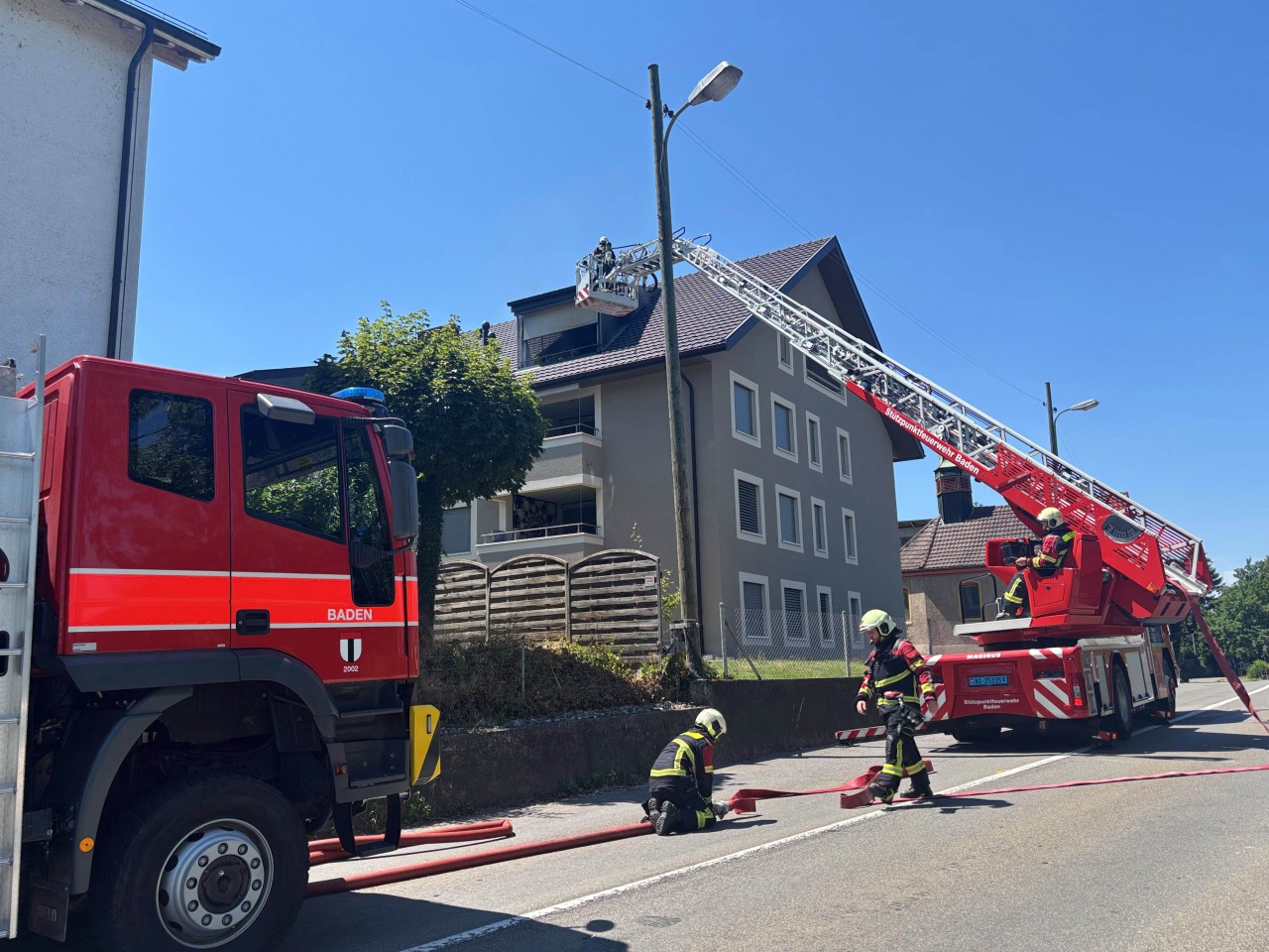 Zwei Feuerwehrfahrzeuge vor einem Mehrfamilienhaus. Drehleiter ausgefahren.