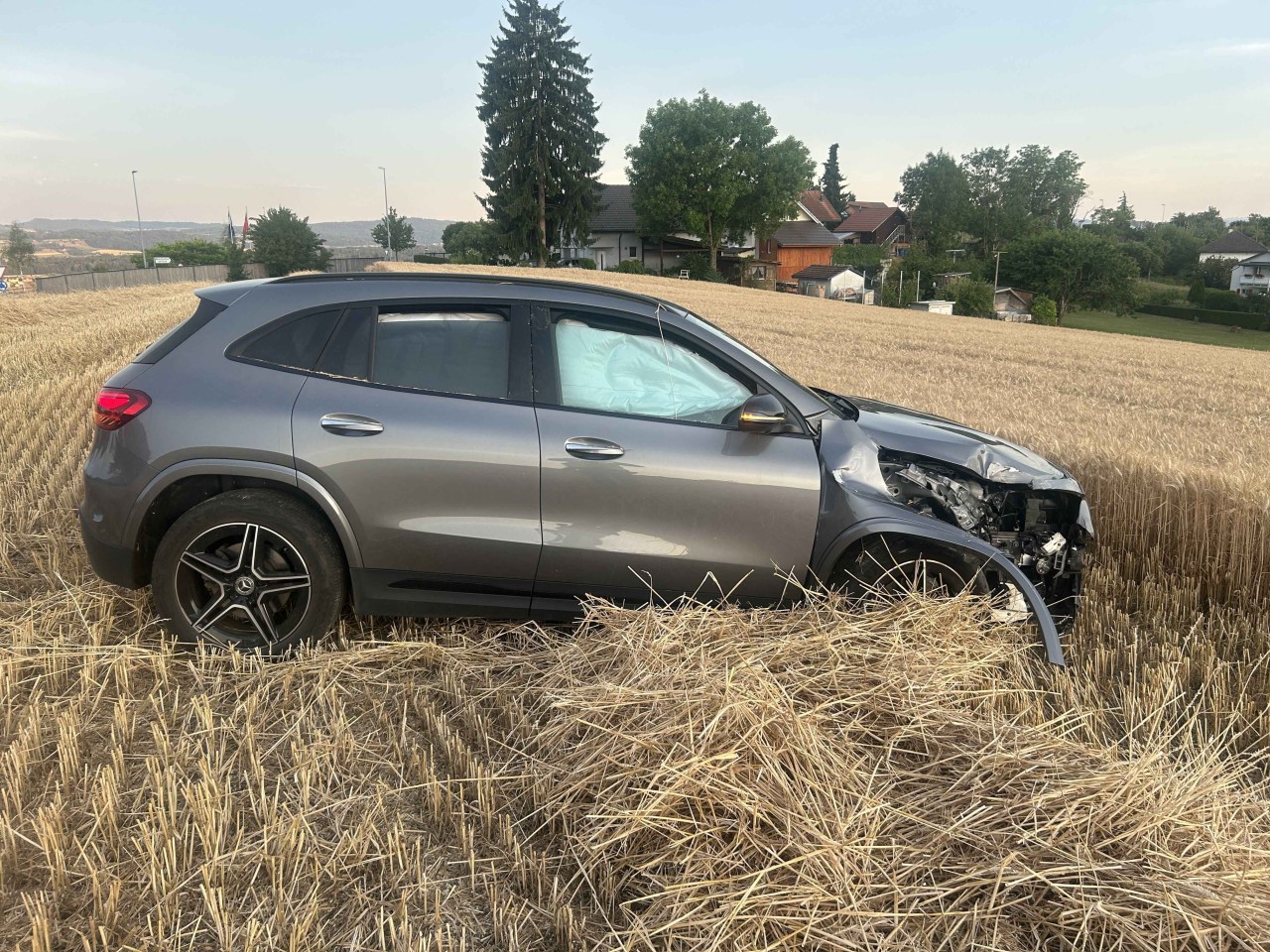 Beschädigtes, graues Fahrzeug steht auf Stoppelfeld. Airbags sind ausgelöst und vorne rechts ist Fahrzeug stark beschädigt.