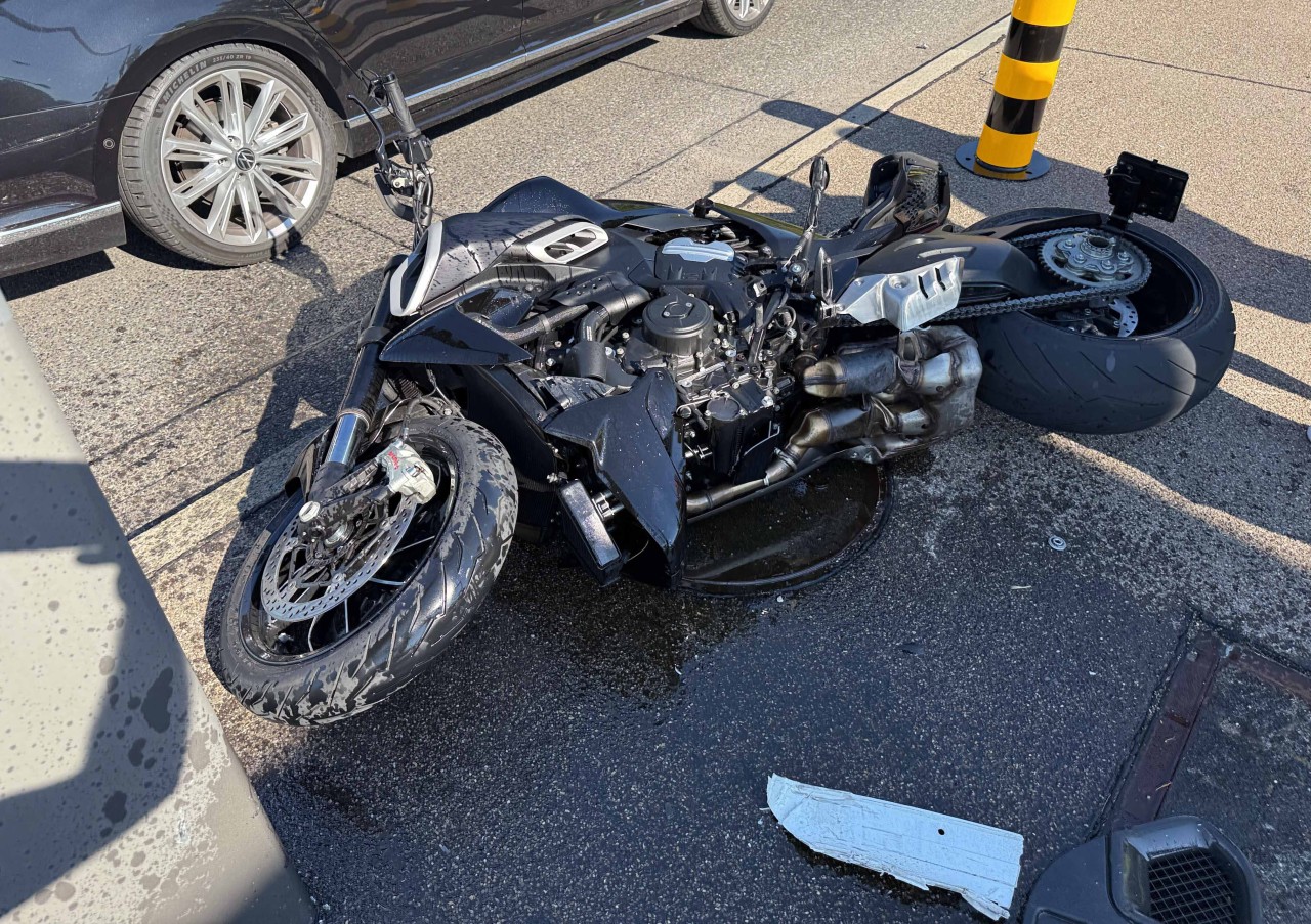 Beschädigtes, schwarzes Motorrad, welches am Boden liegt.