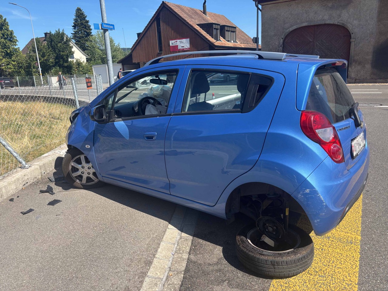 Blaues, beschädigtes Fahrzeug, welches mit einem Zaun kollidiert ist.