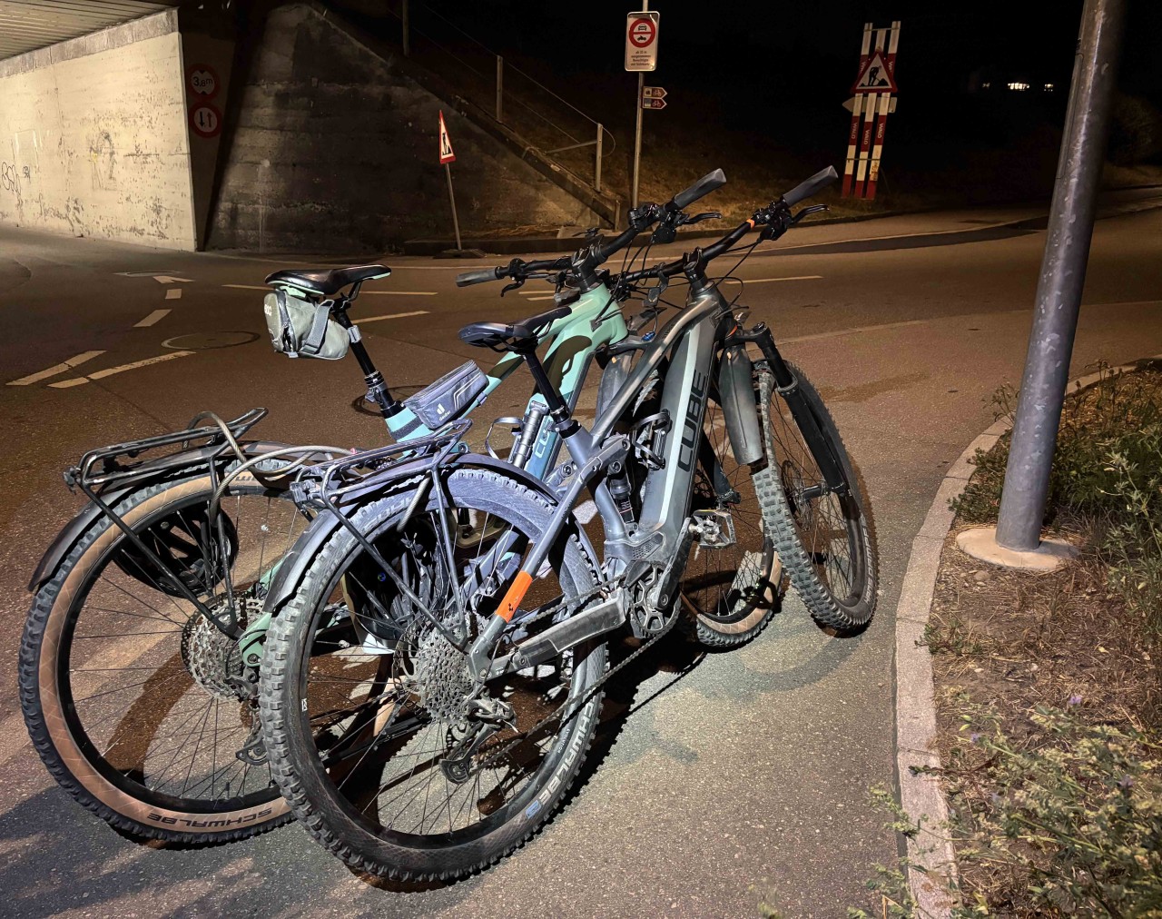 Zwei E-Bikes, welche zusammengekettet sind. Beide von der Marke Cube. Ein grünes sowie ein graues.