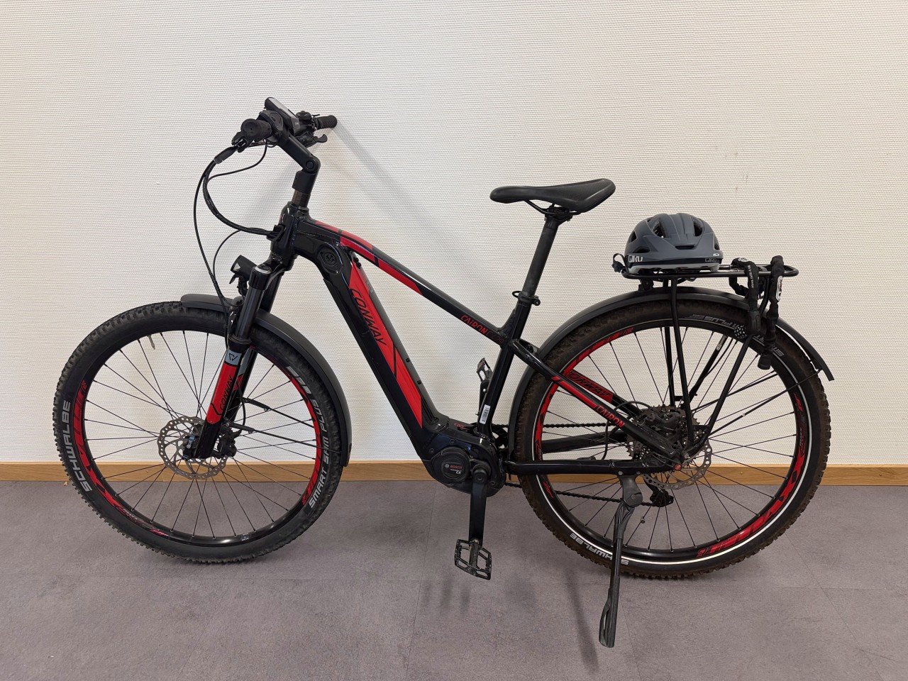 Schwarz-rotes Velo mit Helm auf Gepäckträger.