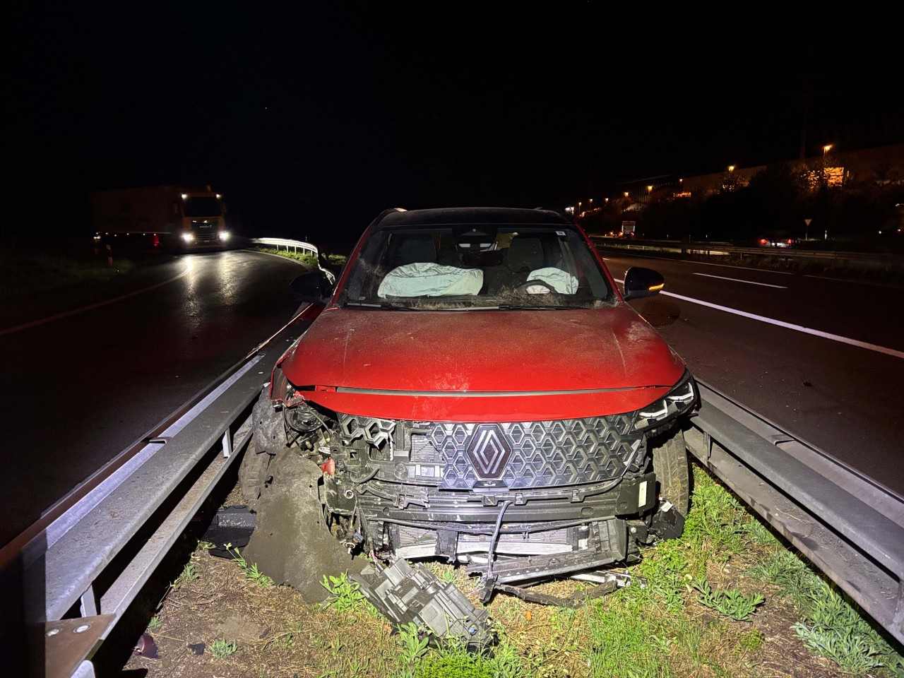 Rotes, beschädigtes Fahrzeug zwischen zwei Leitplanken eingeklemmt.